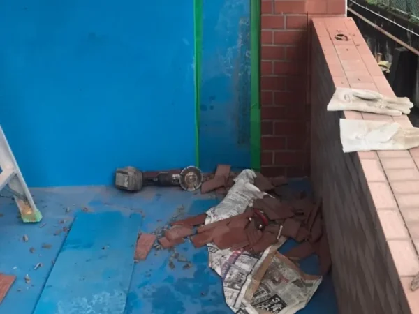 富山でレンガ状の壁タイルを解体。傷つけたくない場所は青いシートで養生し、落としたタイルの破片を回収している様子。