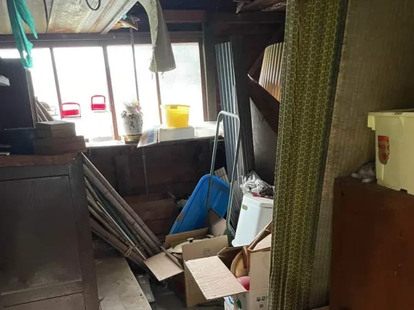 納屋・物置の屋内写真。古い建具や道具類が積み重なっています。