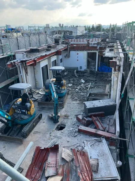 上層で重機2台がビルを解体中。解体した鉄骨は前方にまとめられている。