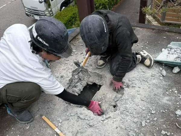 ガレージの屋根に職人が二人。コンクリートに穴をあけている。