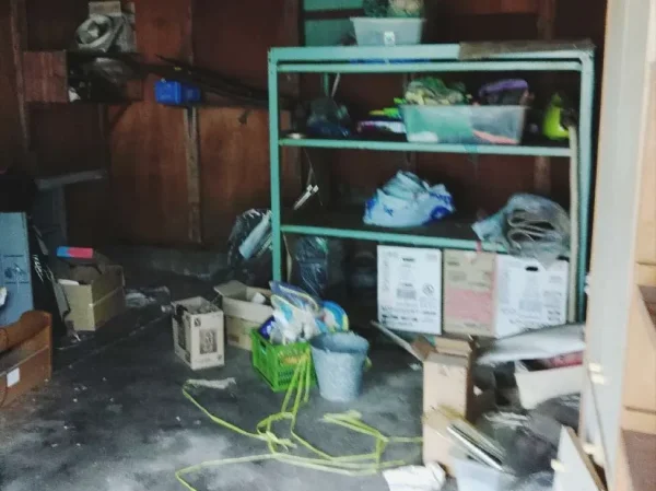 納屋の中の様子。空箱、プラスチック製品、バケツ、棚などが散らばっている。