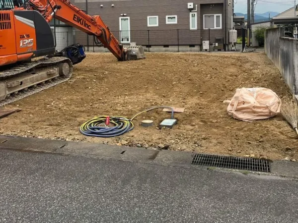 株式会社エイキのオレンジ色の重機が解体後の地面を均等な高さになるよう整えている