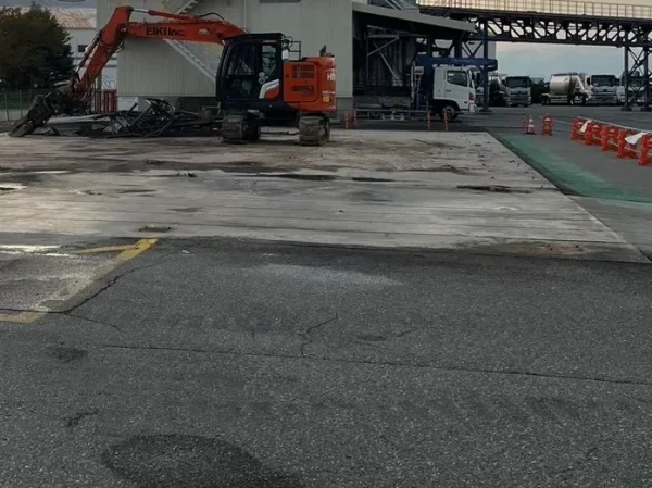 富山市内で風土工事。株式会社エイキのオレンジ色の重機が、地面のコンクリートを解体する直前