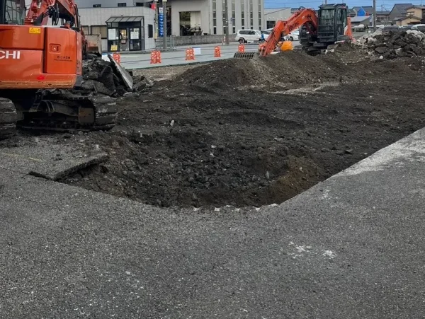 富山市内で風土工事。株式会社エイキのオレンジ色の重機が、2台で盛り上がった土をかき分けている。