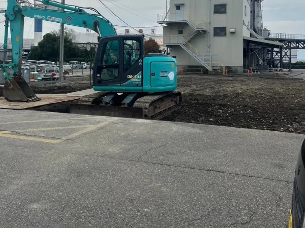 富山市内で風土工事。株式会社エイキの緑色の重機が、整地作業を終えた地面の上に乗っている。