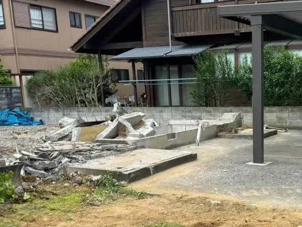 住宅を解体し終え、基礎コンクリートが見える。右手にはカーポートが傷つかずに残っている。