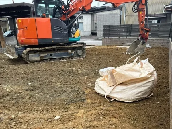 橙色の油圧ショベルで、土地を転圧中。