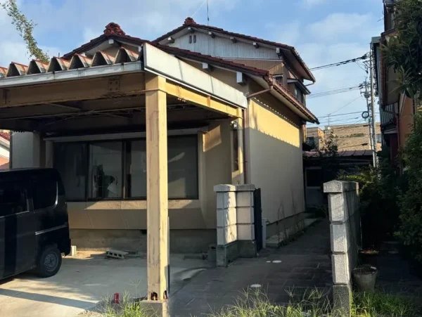 富山市の住宅街にある、二階建て住宅の解体前の姿。前方に鉄製のカーポートがある。