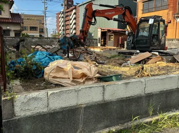 躯体が解体撤去され、重機でコンクリート基礎を解体中。