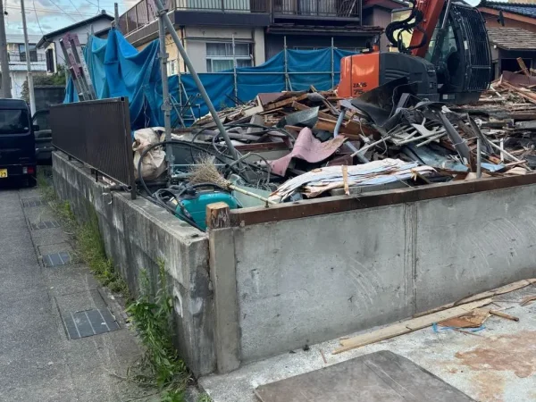 内部解体後、構造体（躯体）を重機が解体中。鉄や木など様々な廃材が山になっている