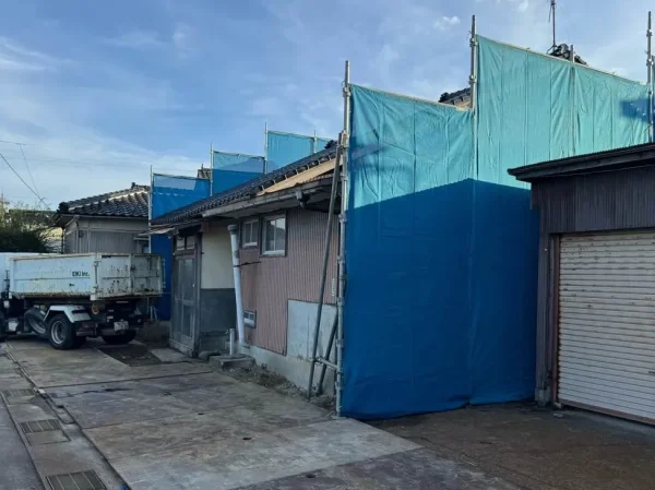 写真の真ん中が、解体する住宅の姿。その住宅の左右に青色の養生が見える。
