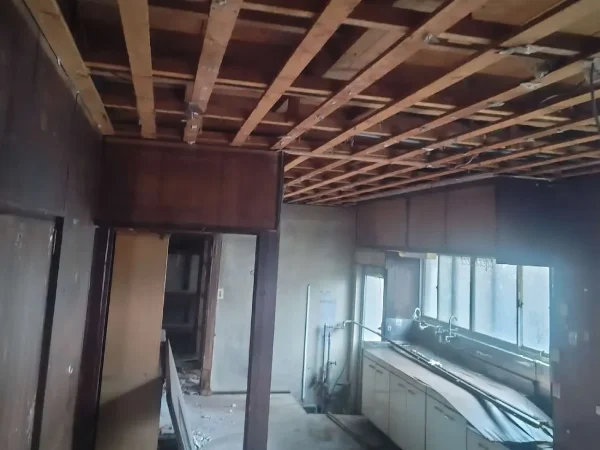 天井板、壁が剥がされ、木の骨組みがむき出しになったキッチン