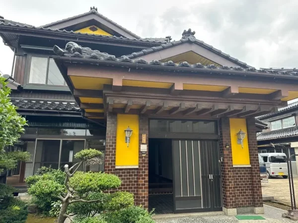 解体する前の和風住宅。立派屋根と植栽があり、玄関も高品質なレンガ状の外壁が使われている。