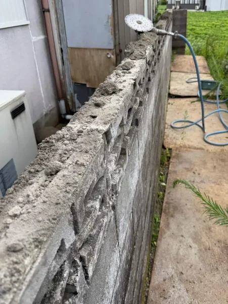 ブロック塀の上にエンジンカッターが置かれ、切り込みが入っている様子