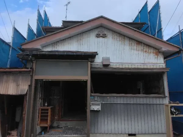 左右、後方の方面を青色シートで養生してある写真。住宅の窓や玄関はすでに撤去してある。