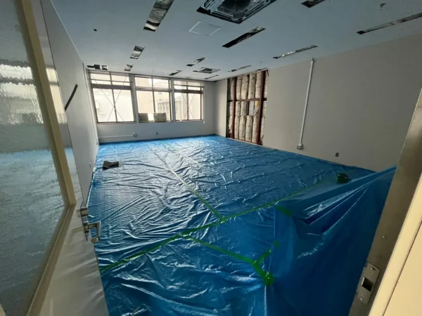 富山の施設内で天井ボードを解体。解体前の状態で、余計な部分を傷つけないようにブルーシートが敷かれている。