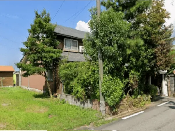 解体前の木造住宅の写真。4本の木々に囲まれている