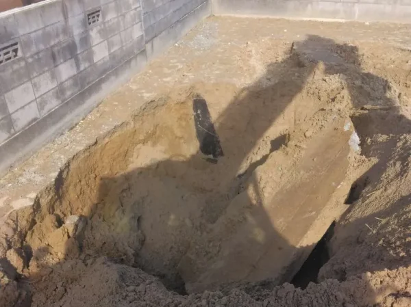 コンクリート塀のそばにユンボの影が見える。