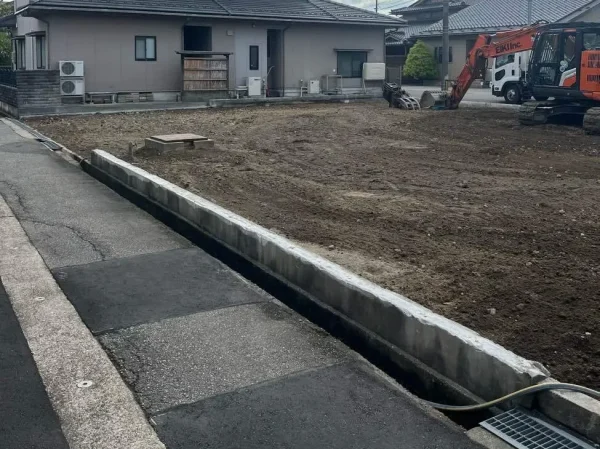 更地化された地面の上に株式会社エイキの重機がある