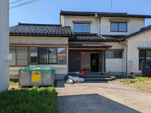 これから解体する二階建ての木造住宅。脚立やコンテナが家の周辺に置かれている