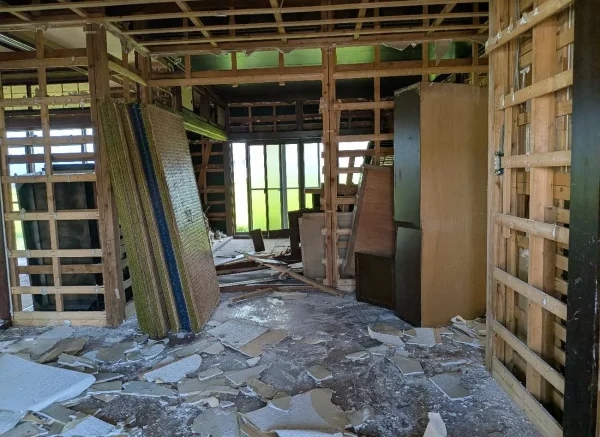 現場住宅の屋内の写真。畳を上げられている。壁紙や石膏ボード、断熱材がはがされている。