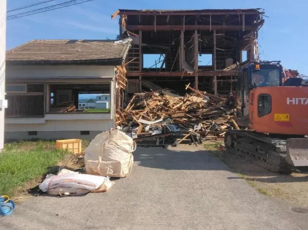 油圧ショベルで、屋外から躯体を解体中。手前に廃材を入れたフレコンバックが見えている。