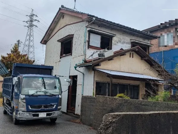 今回の解体工事の現場、２階建ての木造住宅。右側の建物との間を養生シートで囲んだ。