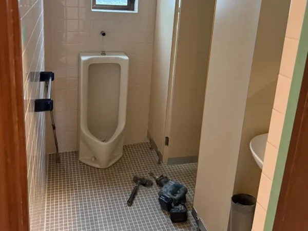 タイルで囲まれたトイレの全景。手前に個室、奥に小便器。