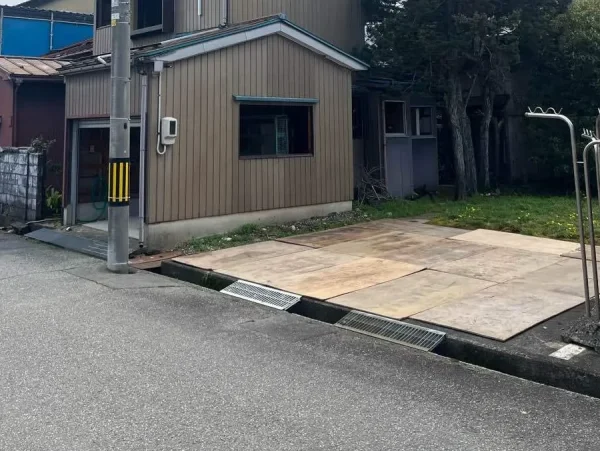 解体する住宅の右側の敷地に、コンパネが敷かれている。