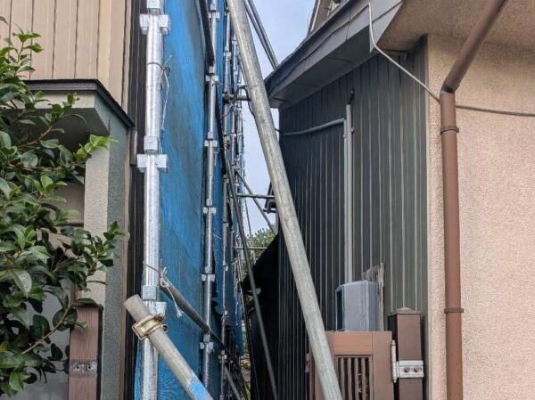 隣家との隙間。お互いの壁の隙間がほとんどない。そこに足場とシートの養生が施されている。