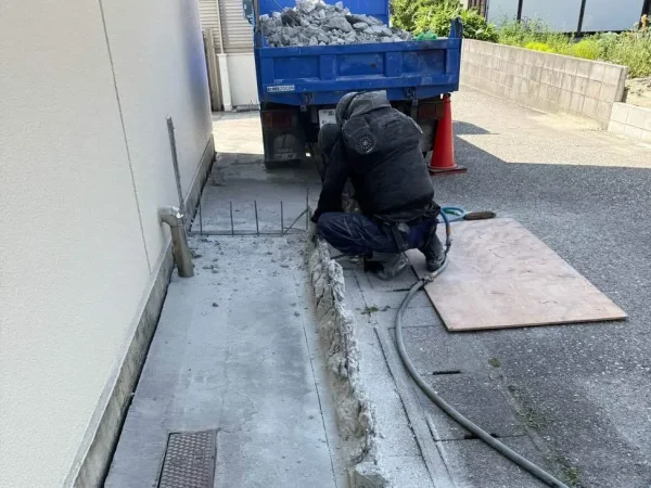 株式会社エイキの職人がブロック塀を斫っている。