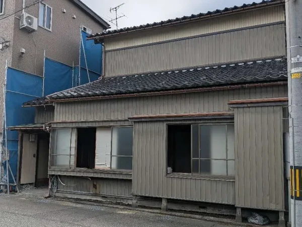 今回解体する住宅。隣の建物と距離がない。その間には、青色のシートが張ってある。