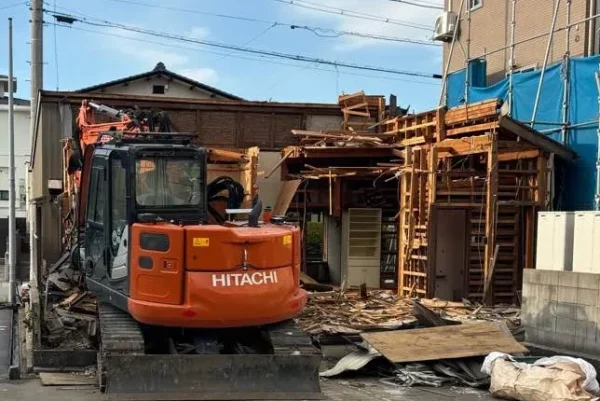 重機が住宅の構造を外から解体している様子。