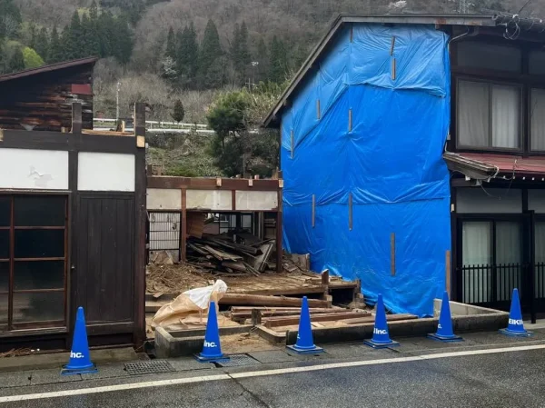 手壊しによる解体が進んでいる写真。現場には青いカラーコーンが6本並んでいる