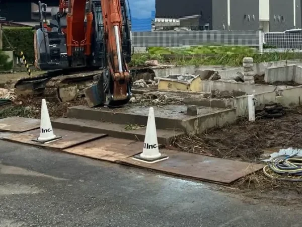 構造体の解体が終わり、基礎コンクリ－トの解体中。 道路と敷地の間には、木や金属の板が置かれている。