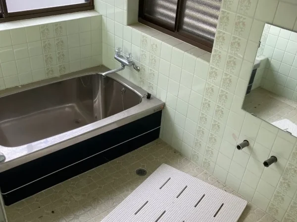 解体前のお風呂場の写真。ステンレス製のバスタブと模様の入ったタイルが映っている。
