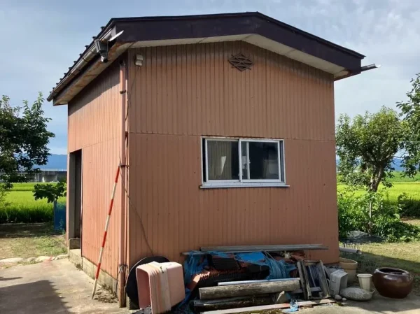 解体前の小屋。外壁はオレンジ色で、中に入っていたものが外に出されている。