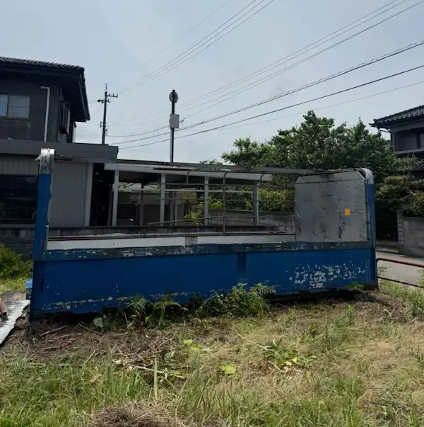 手作業で解体されている古い青のコンテナ