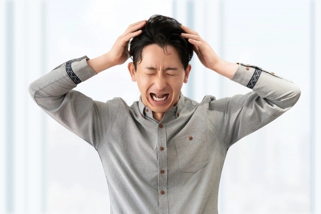 困り果てて、頭を抱えている中年男性。