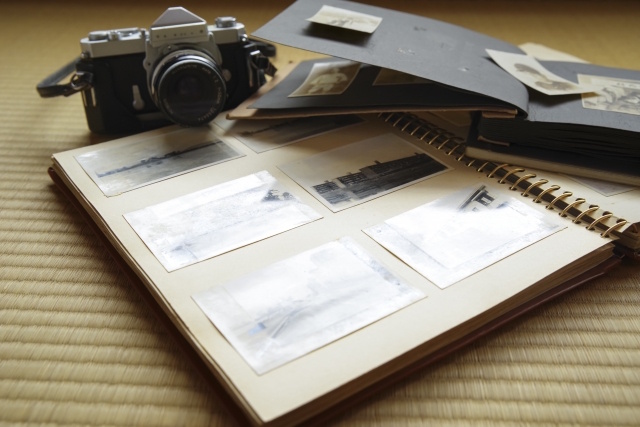 古い写真が入ったアルバムと一眼レフカメラ。