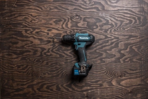 茶色い板の上にマキタ（Makita）の電動ドリルが置かれている
