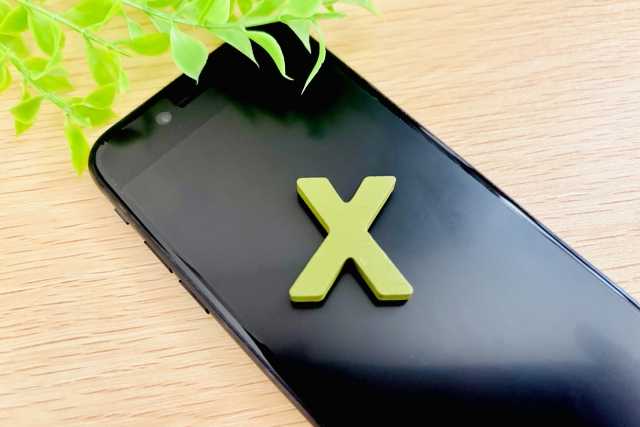 スマホにXのロゴが乗っている様子