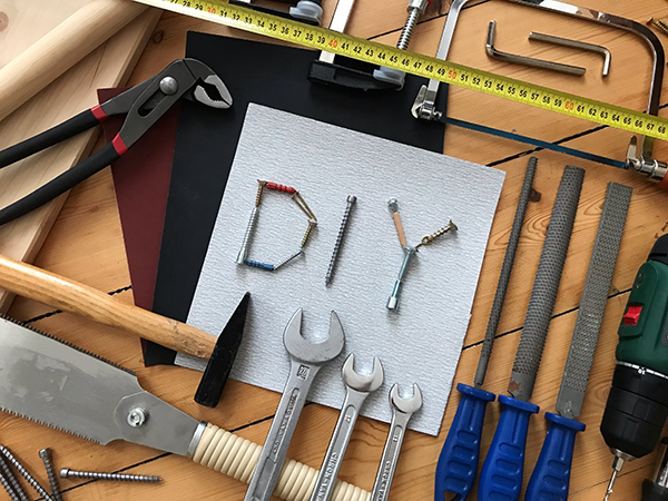 工具が並んでおり、中心にネジで構成された「DIY」という文字がある。